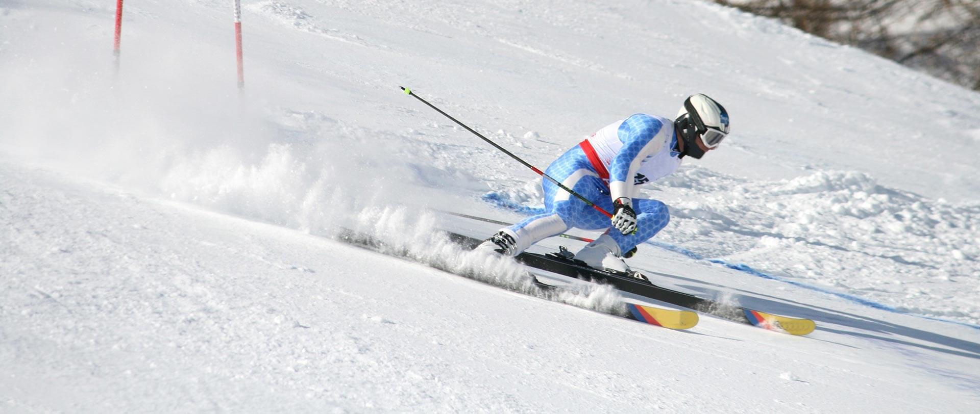 An alpine skier sends snow flying as he plummets down a snowy course.